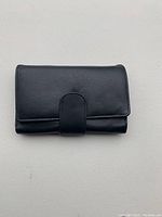 Front view of black soft leather trifold wallet with snap closure.