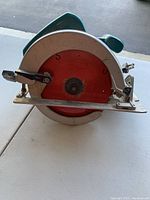 Front view showing circular blade guard and metal base plate with adjustment lever.