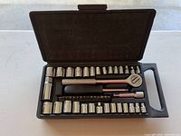 Black ratchet set in plastic case with multiple chrome sockets, ratchet handle and extensions.