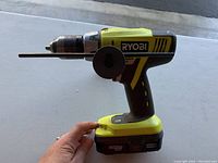 Side view of Ryobi cordless drill showing 18V lithium-ion battery and side handle attachment
