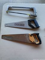 Photo of three saws including a coping saw and two traditional handsaws, one branded Vulcan