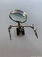 Front view of soldering stand with magnifying glass and helping hands on black base.