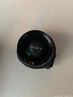 Top view of a small Sony camera lens with front cap showing the Sony logo.