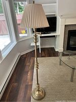 Tall peach floor lamp in front of windows showing base and pleated shade with extendable arm extended.