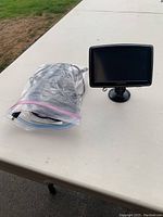 Tomtom GPS device with suction mount displayed next to a plastic bag on a table outside.