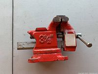 Photo of red metal 3 1/2 inch bench vise from front showing jaw and handle