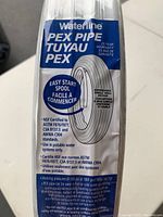 Closeup of product label showing brand Waterline, PEX Pipe, 25 year warranty, and usage instructions including certification info.