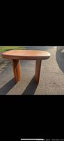 Full view of wooden coffee table showing rounded edges and two solid panel legs from one angle.