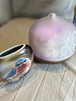 Close-up of aromatherapy oil infuser and ceramic bird container showing detailed floral design and bird painting.