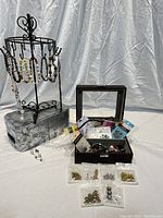 Photo showing multiple handmade beaded bracelets displayed on a metal stand. Beside the stand is a jewelry box containing various beads and charm packs. Small packs of spacer beads laid out in front.