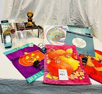 Photo of the garden flags laid out with wind spinner accessories and small decorative items, showing flags with pumpkin and teddy bear designs along with Helix wind spinners.