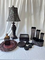 Photo showing the ornamented table lamp, handmade glass bottle, wooden tray, wooden box, set of three vases, desk organizer, and multiple coasters.