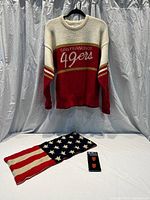 Full view of vintage San Francisco 49ers sweater hanging with knit American flag scarf and San Francisco Giants socks displayed below