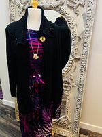 Front view of mannequin wearing purple and pink animal print dress with black cardigan and gold-tone necklace pendant.