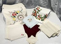 Photo showing the full assortment of embroidered tablecloth and napkins in various colors and embroidery styles.