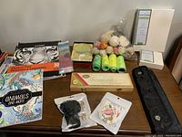 Image showing multiple sketchbooks, embroidery threads, pastel sticks, paint brushes and packaged drawing accessories on a table.