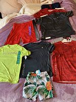 Overview of kids' swim shorts and sports shirts in various colors from Spyder brand, many with tags