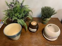 Overall view of artificial plants, ceramic planters, and bank on wooden surface