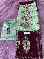 Set showing folded light green shirt next to folded embroidered sari on purple fabric background.
