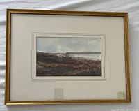 Framed watercolour showing a boat on land in a landscape setting with muted colors and cloudy sky. Visible signature bottom left. Overall excellent condition.