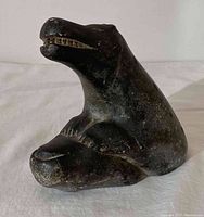 Front side view of dark stone carved polar bear with cub, showing detailed carving and open mouth of the bear.