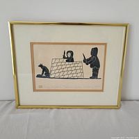 Framed print showing Inuit figures building an igloo, with a dog sitting.