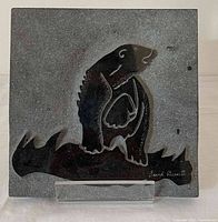 Front view of square marble plaque with engraved Inuit style polar bear design and signature in lower right corner.