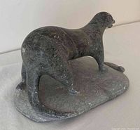 Side and rear view of dark stone Inuit otter carving on base