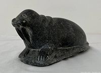 Front-side view showing walrus stone carving details such as face, flippers, and surface texture.