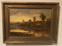 Oil on board landscape painting in an ornate gilt frame showing a sunset rural scene with river, houses, church tower and trees.