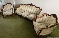 Three-seat sofa and two matching armchairs arranged on green carpet