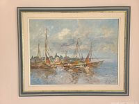 Framed oil painting depicting several sailing boats moored at a dock under a cloudy sky, signed lower right.