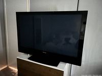Front view of black 50-inch Pioneer plasma TV turned off on a wooden piece of furniture.