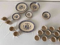Overall arrangement of plates, bowls, teacups and mugs on white surface