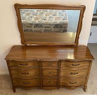 Large dresser in medium brown veneer with scalloped drawer fronts topped by attached rectangular mirror