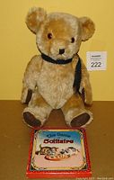 Front view of vintage mohair teddy bear sitting behind The Game of Solitaire box featuring illustrated cats on the lid.