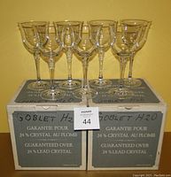 Seven clear lead crystal water goblets arranged on their original boxes showing the guarantee label and handwritten 'Goblet H2O' text.
