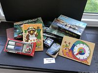 Photo showing assorted vintage games and puzzles including Crown & Anchor, wood puzzles, 1000-piece jigsaw puzzle, poker chip set in box, and a clock design puzzle.