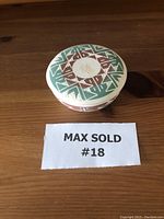 Top view of the Sioux pottery bowl showing the geometric painted design in green and brown on a cream-colored ceramic.