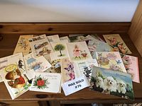 Overview of all vintage greeting cards laid out on wooden surface showing quantity and design variety.