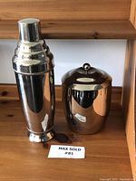 Front view of the tall vintage cocktail shaker and the Copco ice bucket side by side on a wooden surface