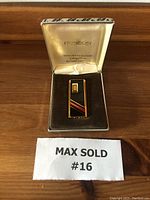 Vintage Ronson butane lighter placed inside original Ronson case on a wooden surface, showing the front of the lighter and case interior branding.