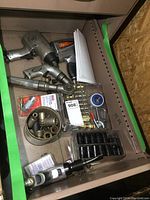 Overview of air tools and accessories arranged in drawer, showing two impact wrenches, air ratchet, air drill, air chisel, impact sockets, fittings, and nozzle in plastic trays and loose.