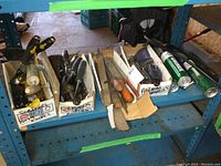 Overview photo of the assortment of chisels, files, scrapers, and grease tubes on workshop shelf.