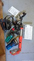 Full lot of power tools and accessories including drill, jig saw, flashlights, hair dryer, and heat shrink tubing shown together on floor.