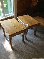 Pair of solid wood end tables shown near a window with sunlight highlighting grain and shape.