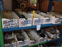 10 cardboard boxes labeled with GM and AC parts logos on industrial shelving with various workshop items inside.