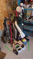 Full view of the golf bag standing on the floor with the golf cart next to it, boxes of golf balls and tees, and accessories in front.