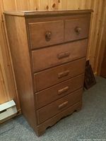 Full view of the wooden highboy dresser with five drawers and wooden knobs and handles in a warm natural finish.