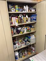 Full view of beige storage cabinet interior showing the assortment of household maintenance items, cleaning supplies, pest control, and small hardware accessories arranged on five shelves.